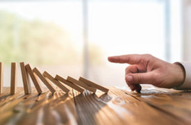 Hand knocking over dominoes