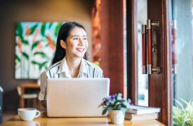 Woman Smiling on Laptop. Liability Insurance Rate Reduction.