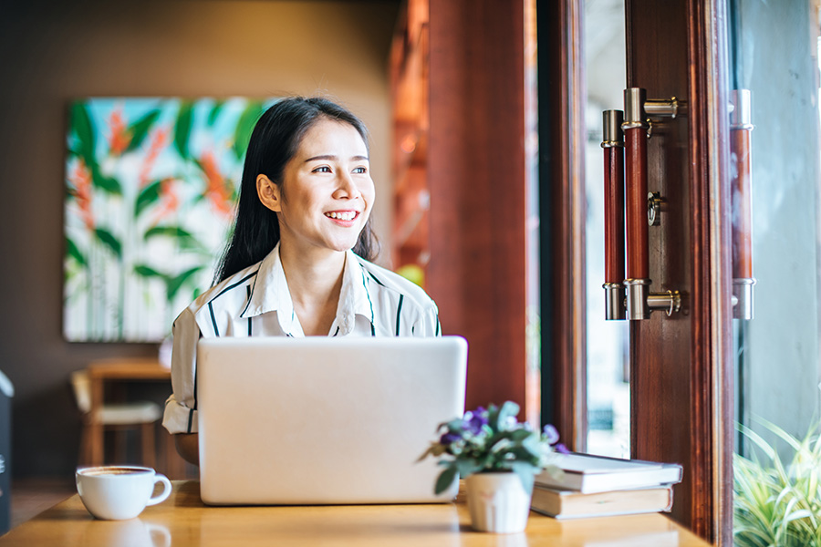 Woman Smiling on Laptop. Liability Insurance Rate Reduction.