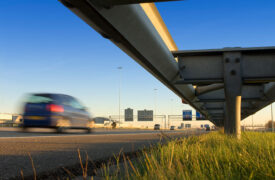 Car speeding past guardrails busy highway
