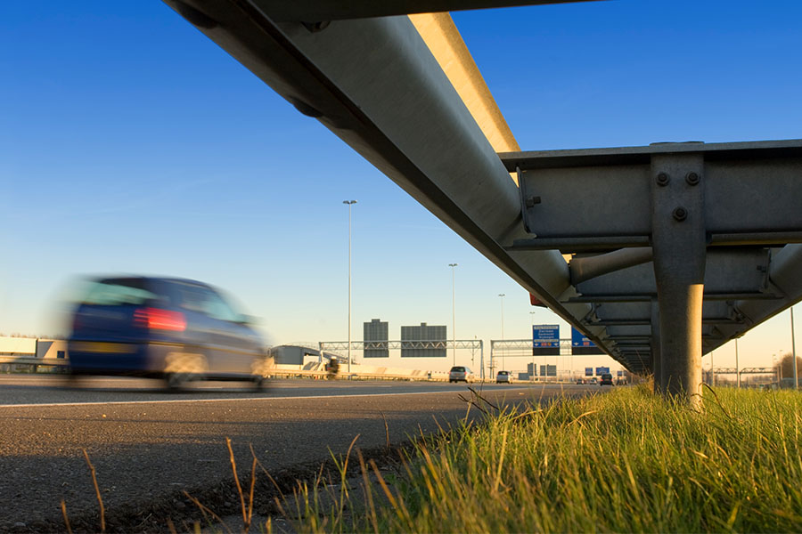 Car speeding past guardrails busy highway